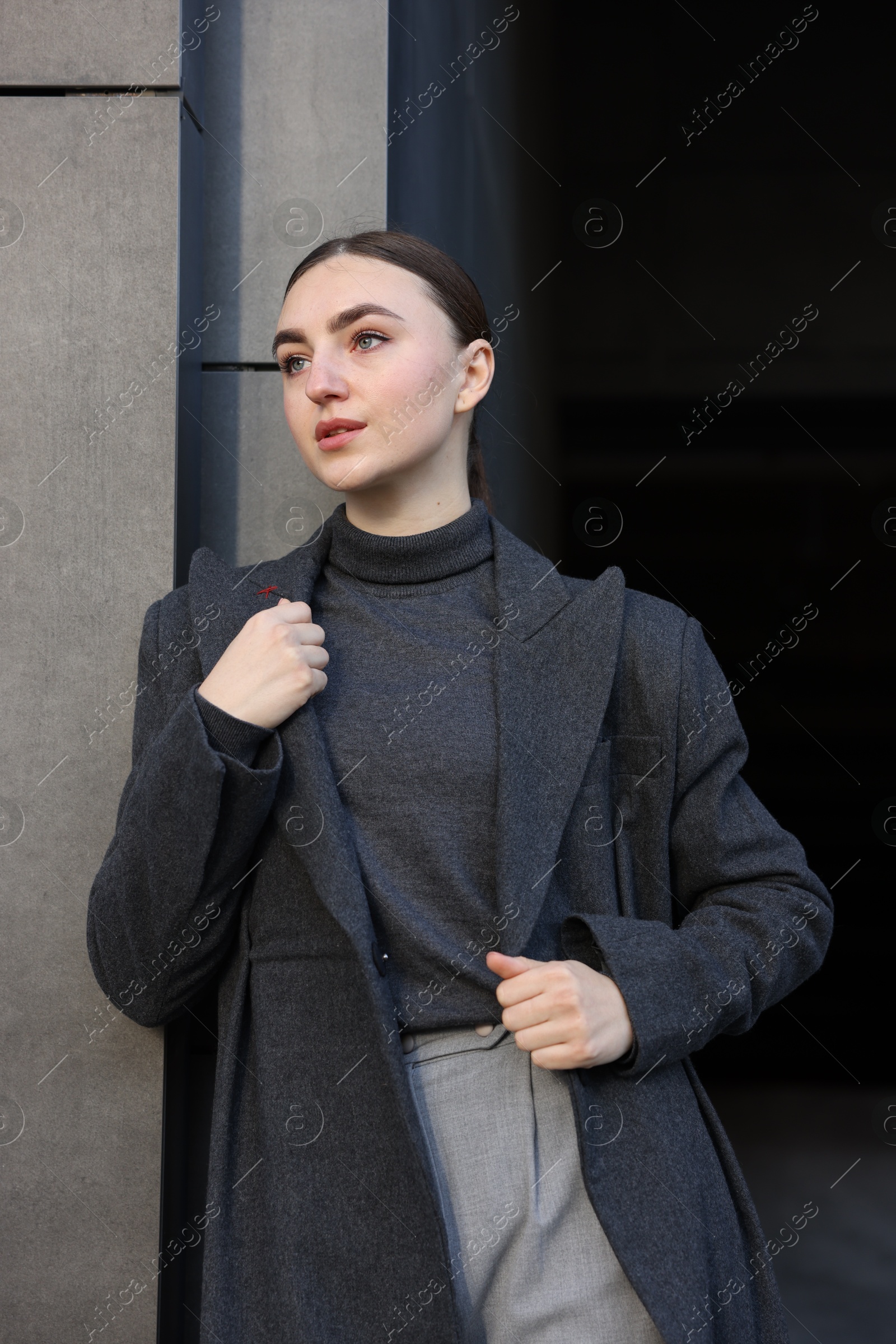 Photo of Beautiful young woman with black coat posing outdoors