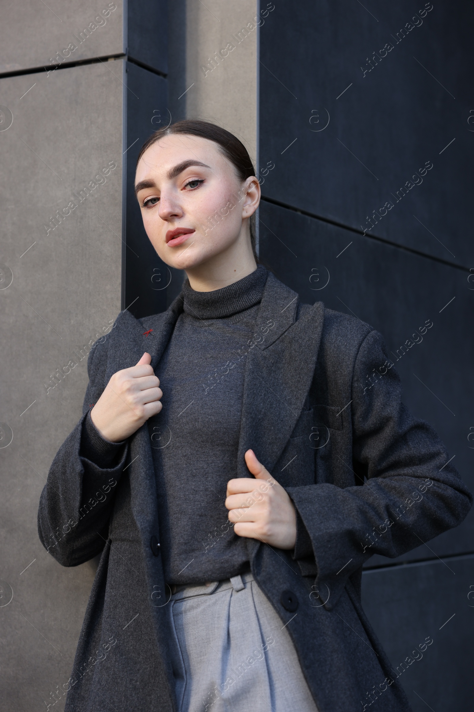 Photo of Beautiful young woman with black coat posing outdoors