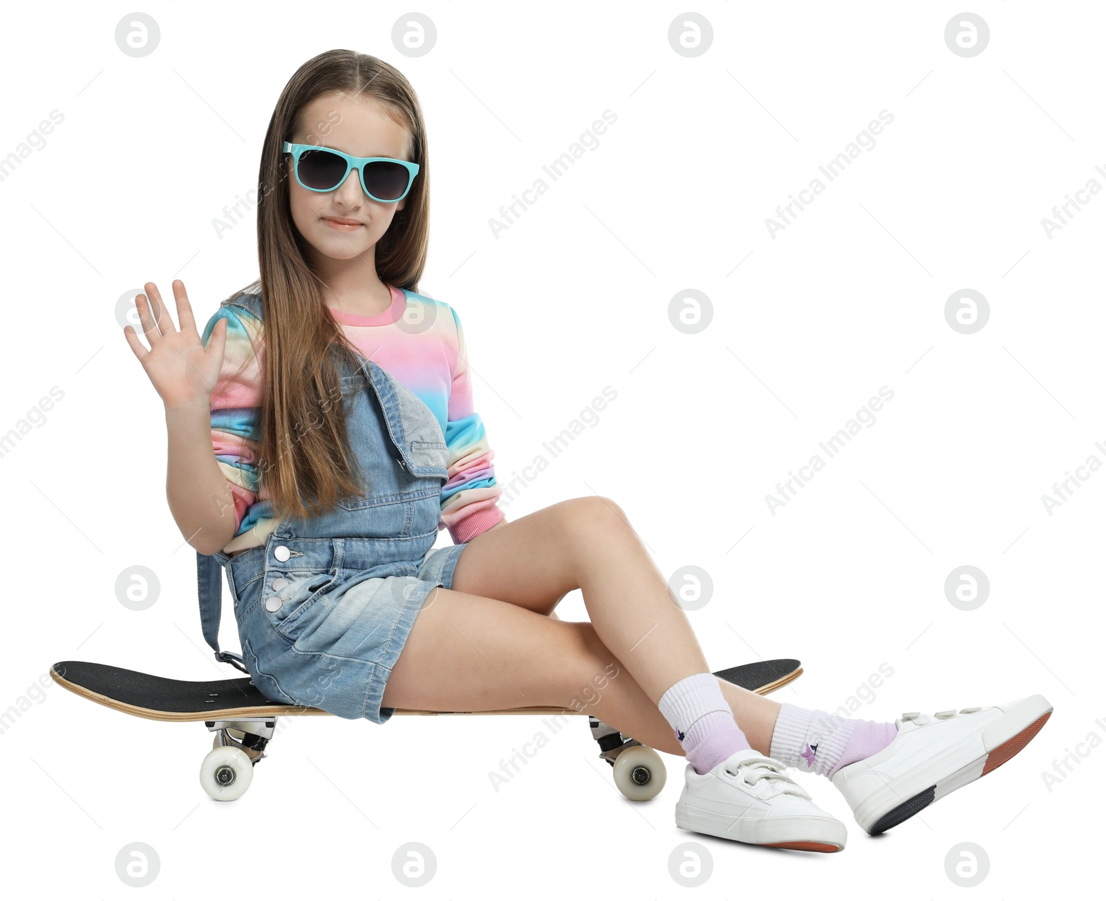 Photo of Stylish girl in glasses sitting on skateboard against white background