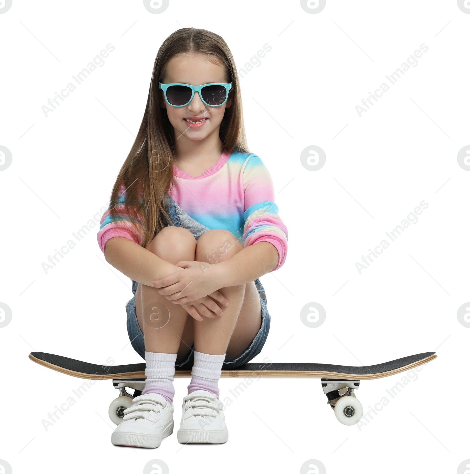 Photo of Stylish girl in glasses sitting on skateboard against white background