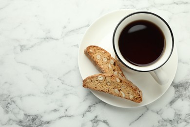 Photo of Traditional Italian almond biscuits (Cantucci) and cup of coffee on white marble table, top view. Space for text