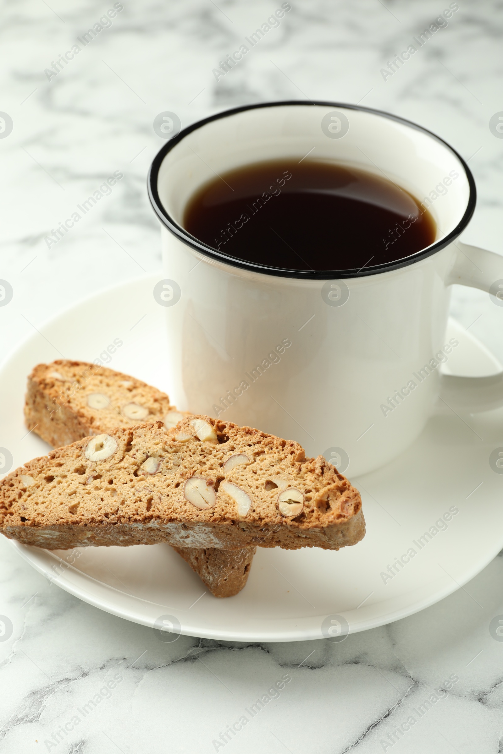 Photo of Traditional Italian almond biscuits (Cantucci) and mug of coffee on white marble table, closeup