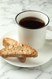 Photo of Traditional Italian almond biscuits (Cantucci) and mug of coffee on white marble table, closeup