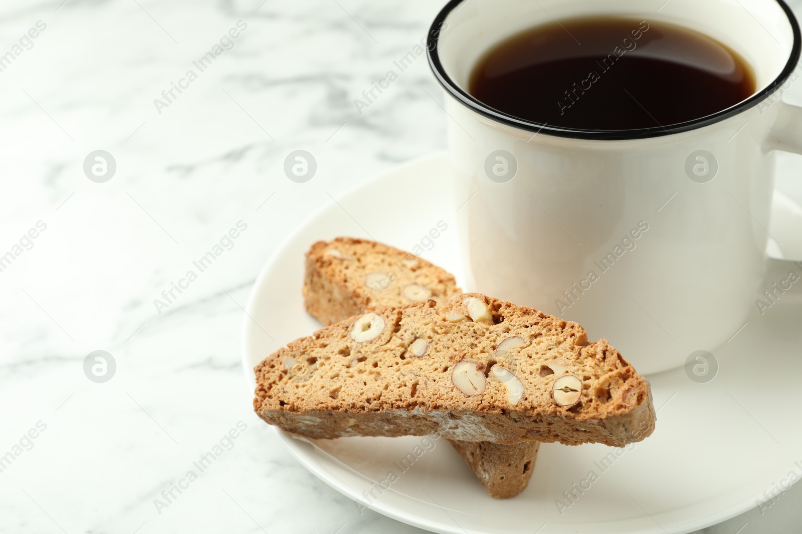 Photo of Traditional Italian almond biscuits (Cantucci) and mug of coffee on white marble table, closeup. Space for text