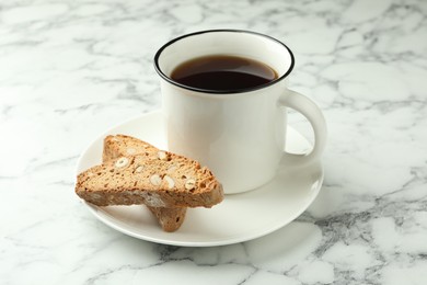 Photo of Traditional Italian almond biscuits (Cantucci) and mug of coffee on white marble table, closeup