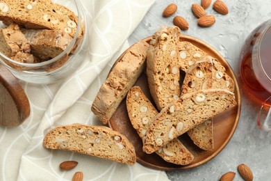 Photo of Traditional Italian almond biscuits (Cantucci), nuts and tea on grey textured table, flat lay