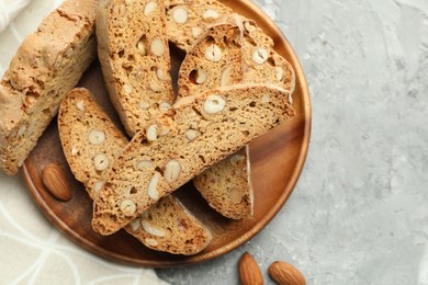 Photo of Traditional Italian almond biscuits (Cantucci) and nuts on grey textured table, flat lay. Space for text