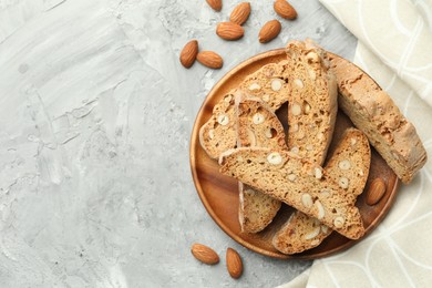 Photo of Traditional Italian almond biscuits (Cantucci) and nuts on grey textured table, flat lay. Space for text