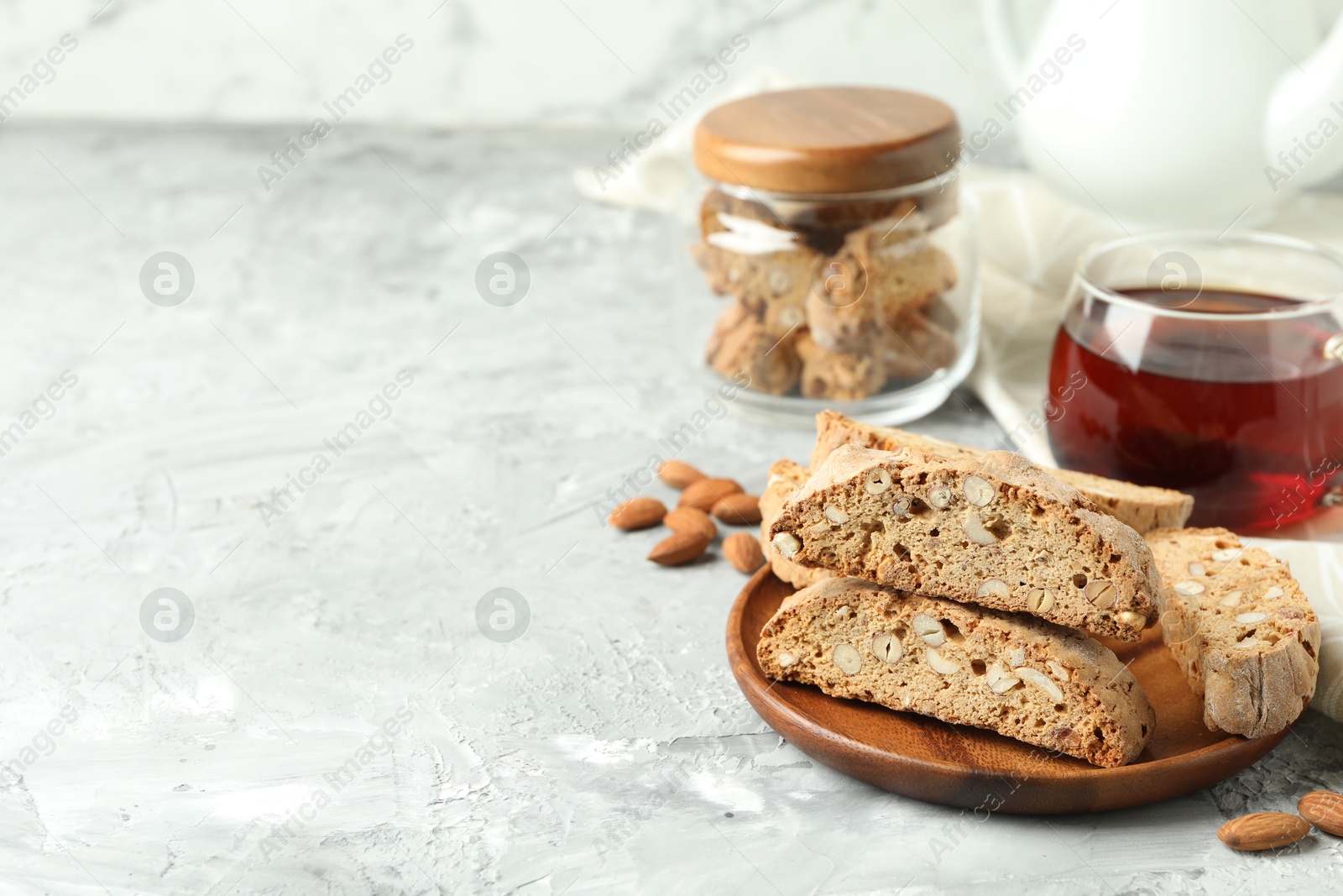 Photo of Traditional Italian almond biscuits (Cantucci) and tea on grey textured table, closeup. Space for text