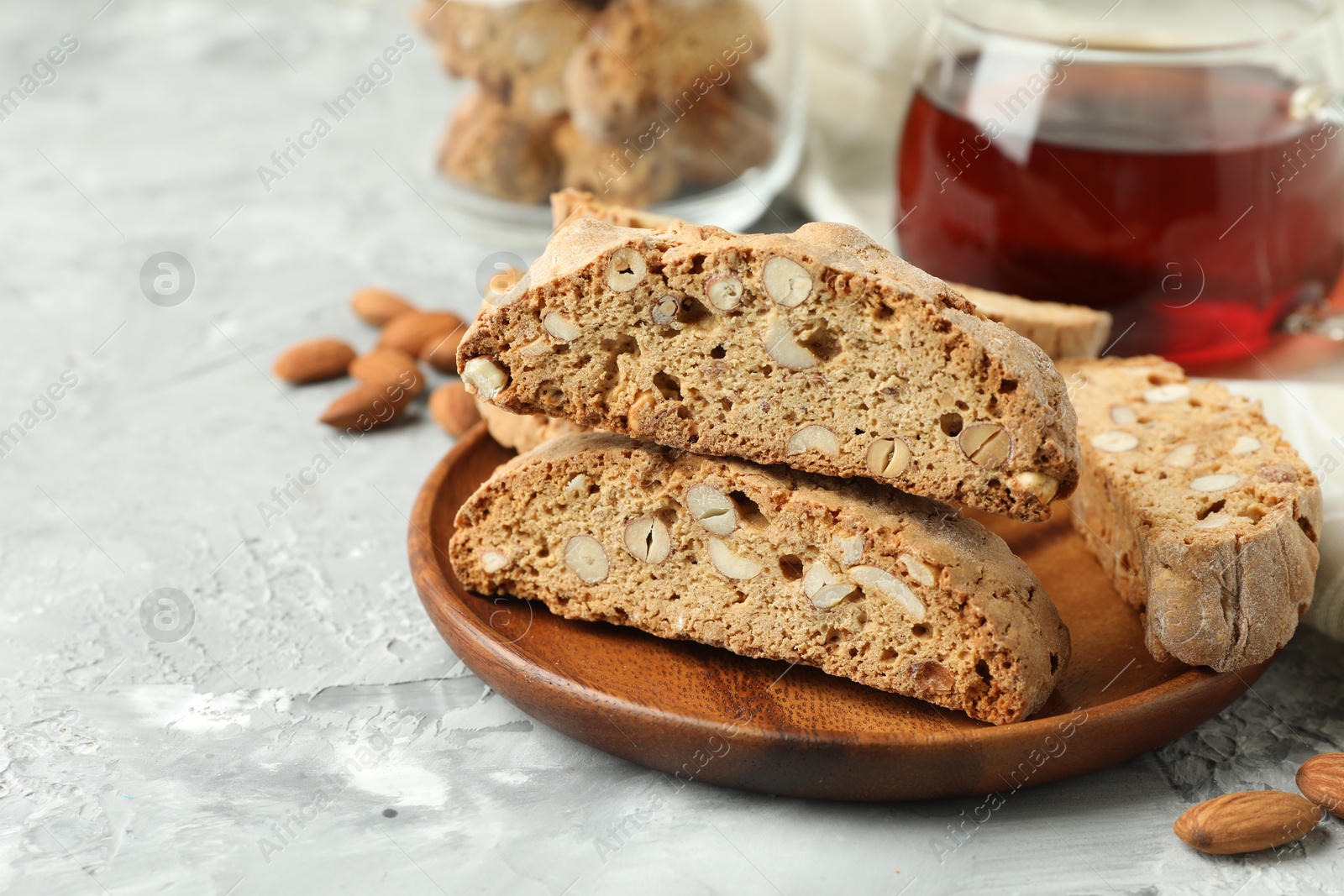 Photo of Traditional Italian almond biscuits (Cantucci) and tea on grey textured table, closeup. Space for text