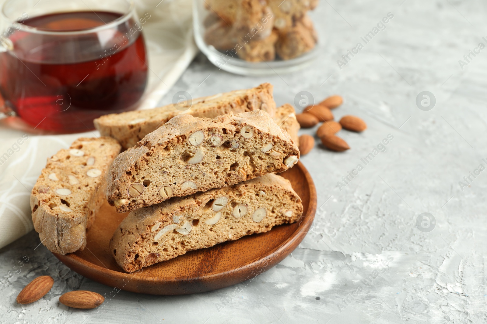 Photo of Traditional Italian almond biscuits (Cantucci) and tea on grey textured table, closeup. Space for text