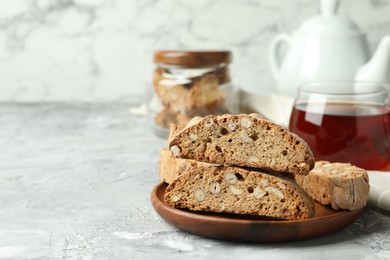 Photo of Traditional Italian almond biscuits (Cantucci) and tea on grey textured table, closeup. Space for text