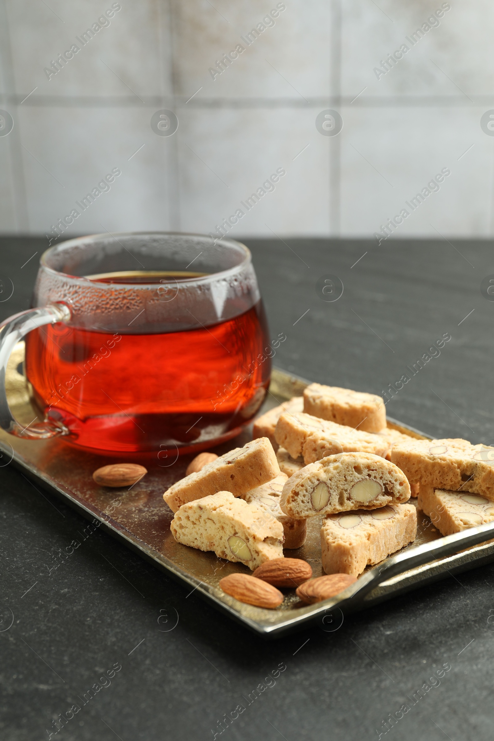 Photo of Traditional Italian almond biscuits (Cantucci), nuts and cup of tea on grey textured table, closeup