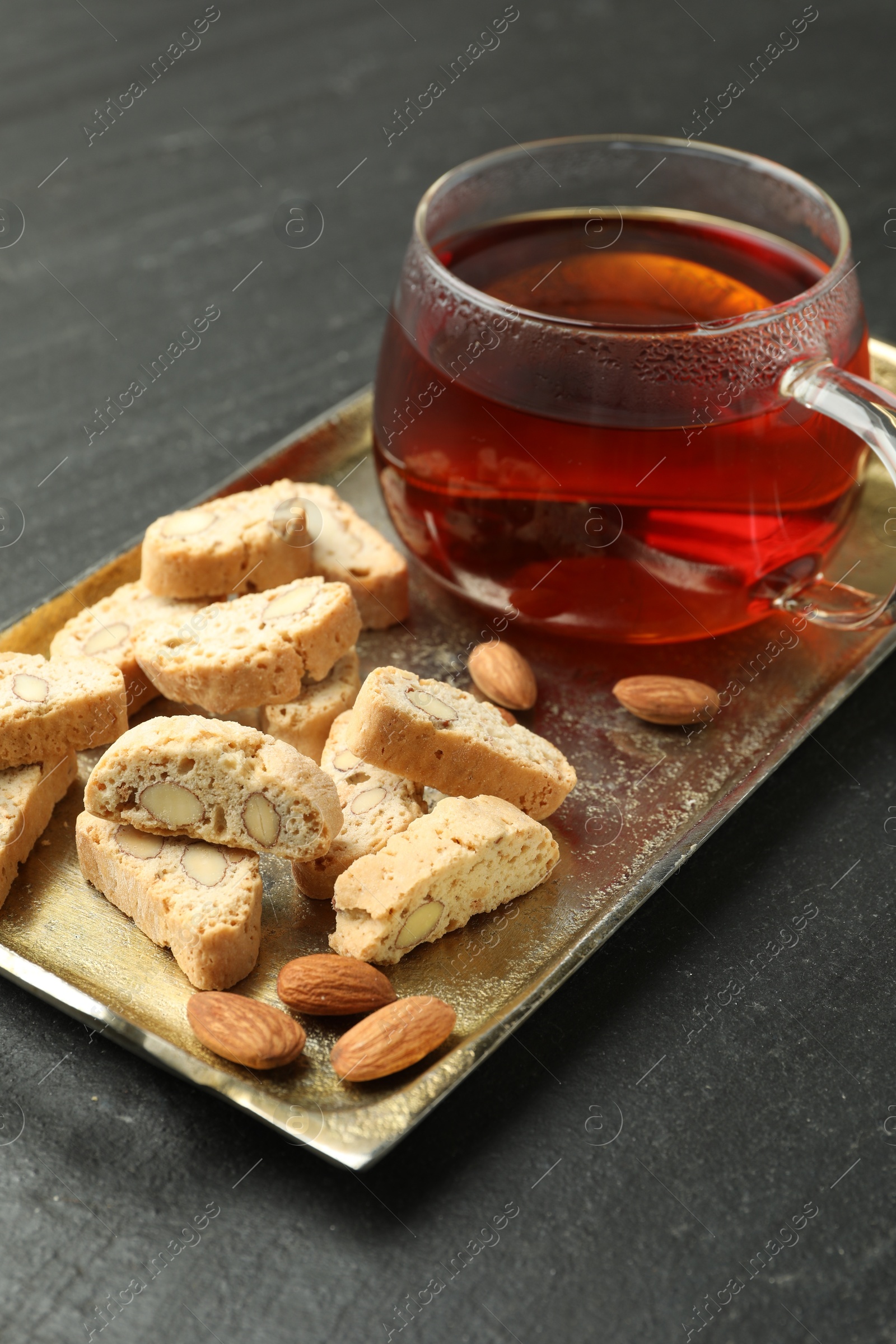 Photo of Traditional Italian almond biscuits (Cantucci), nuts and cup of tea on grey textured table, closeup