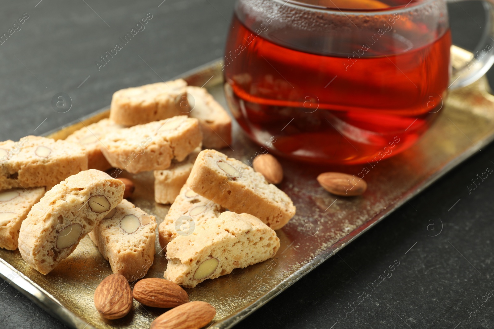 Photo of Traditional Italian almond biscuits (Cantucci), nuts and cup of tea on grey textured table, closeup