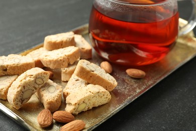 Photo of Traditional Italian almond biscuits (Cantucci), nuts and cup of tea on grey textured table, closeup