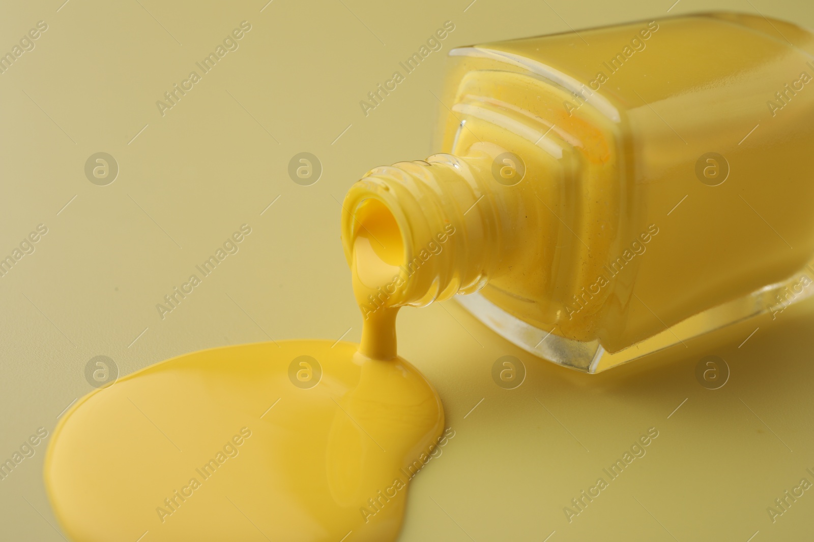 Photo of Bottle of nail polish on yellow background, closeup