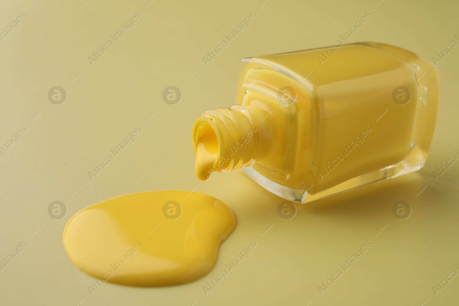 Photo of Bottle of nail polish on yellow background, closeup