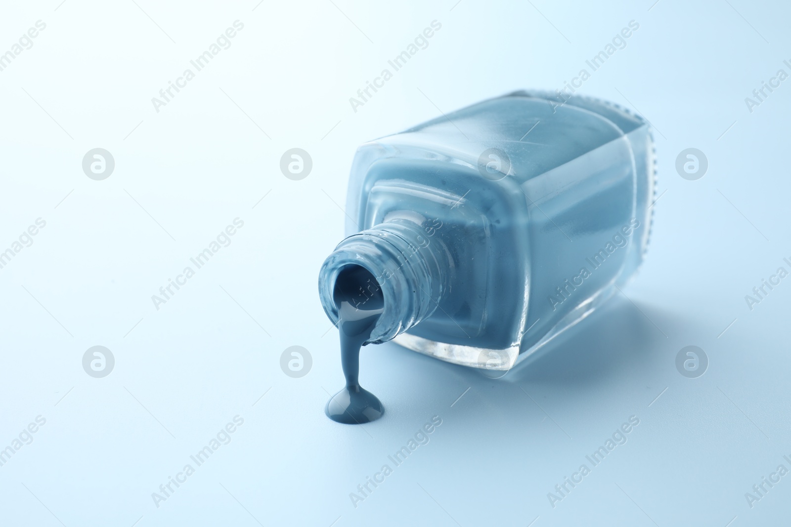 Photo of Bottle of nail polish on light blue background, closeup. Space for text