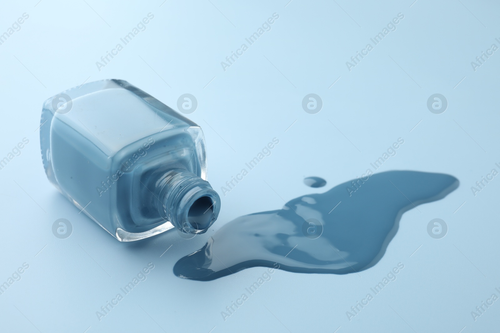 Photo of Bottle of nail polish on light blue background, closeup