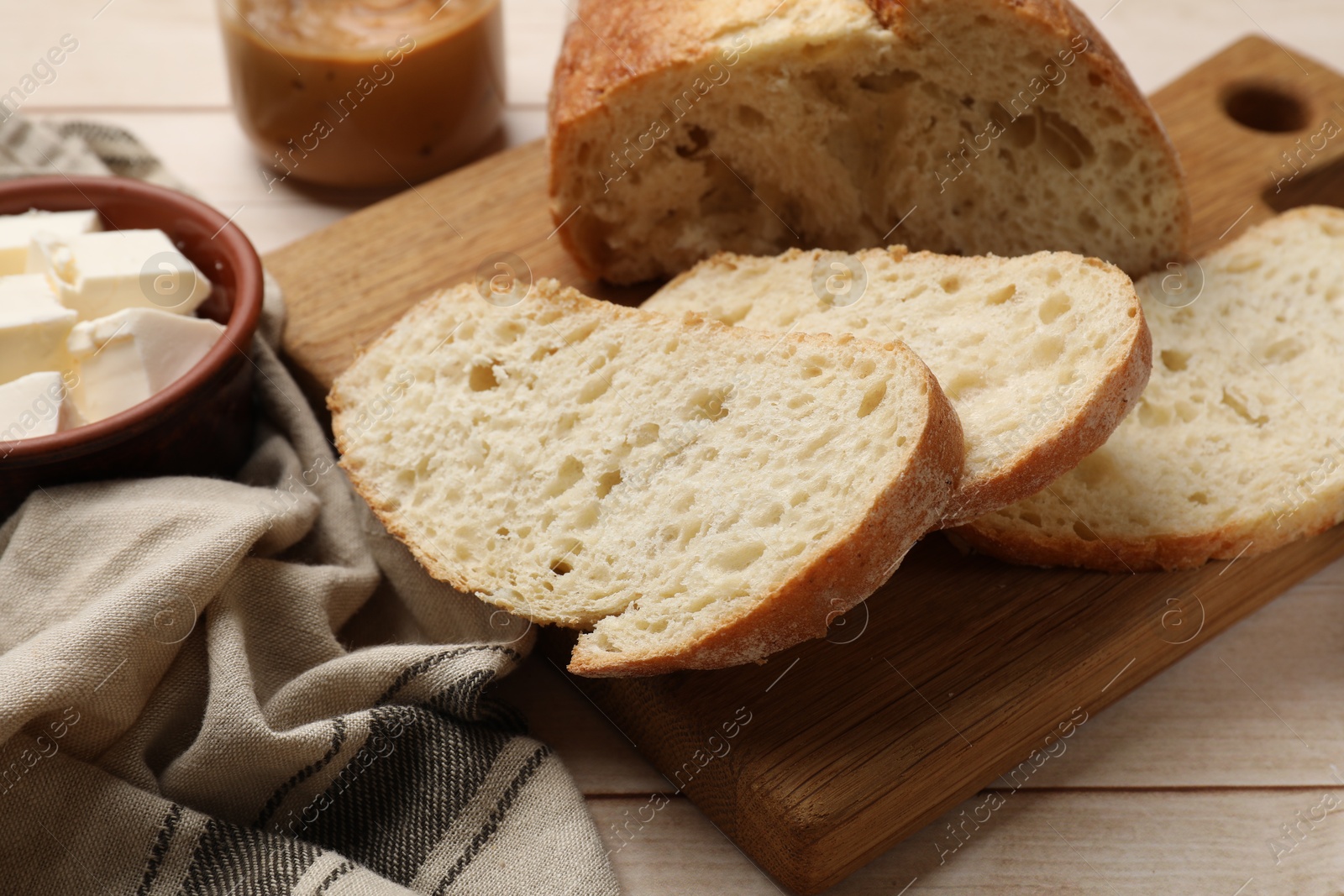 Photo of Cut bread and butter on wooden table, closeup