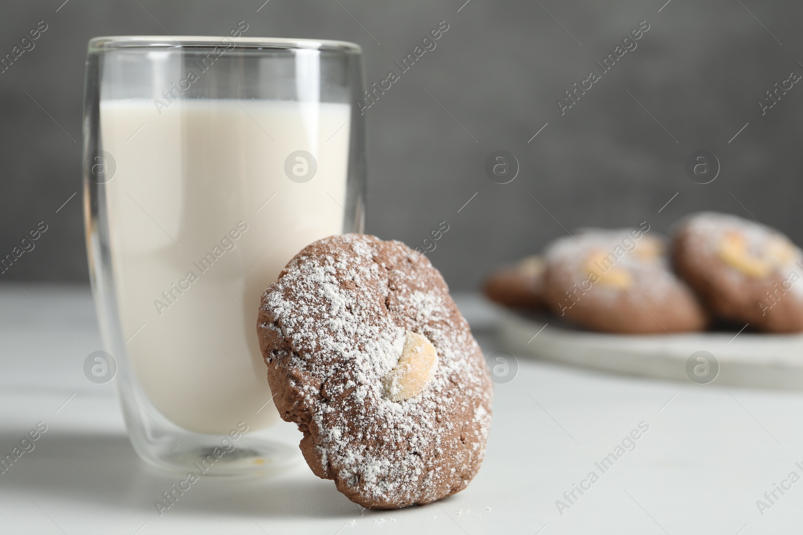 Photo of Tasty chocolate cookie with cashew and glass of milk on white table, closeup. Space for text