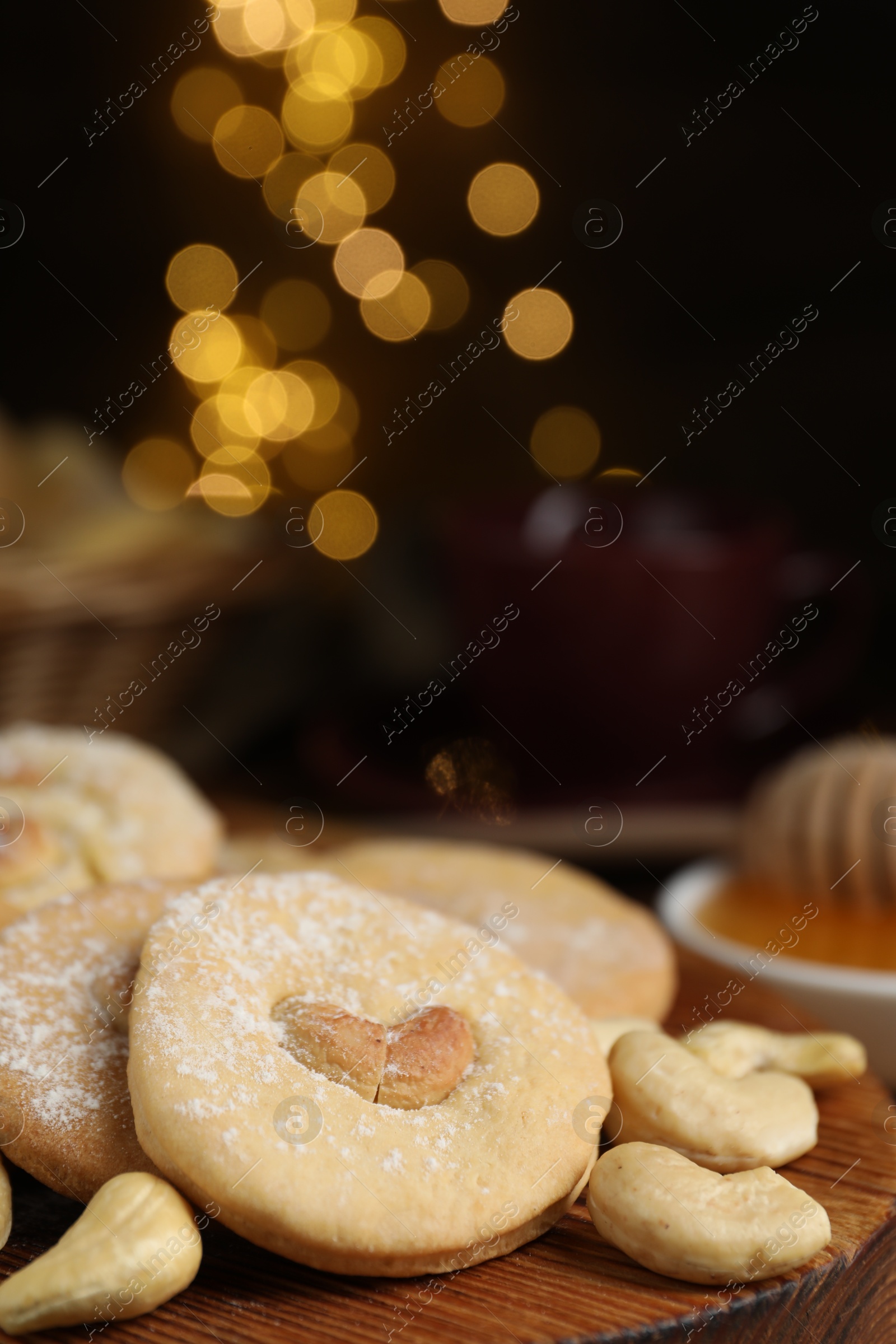 Photo of Tasty cashew cookies with powdered sugar on table, closeup. Space for text