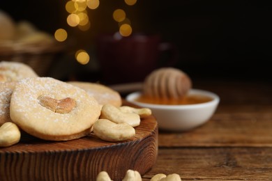 Photo of Tasty cashew cookies with powdered sugar on wooden table, closeup. Space for text