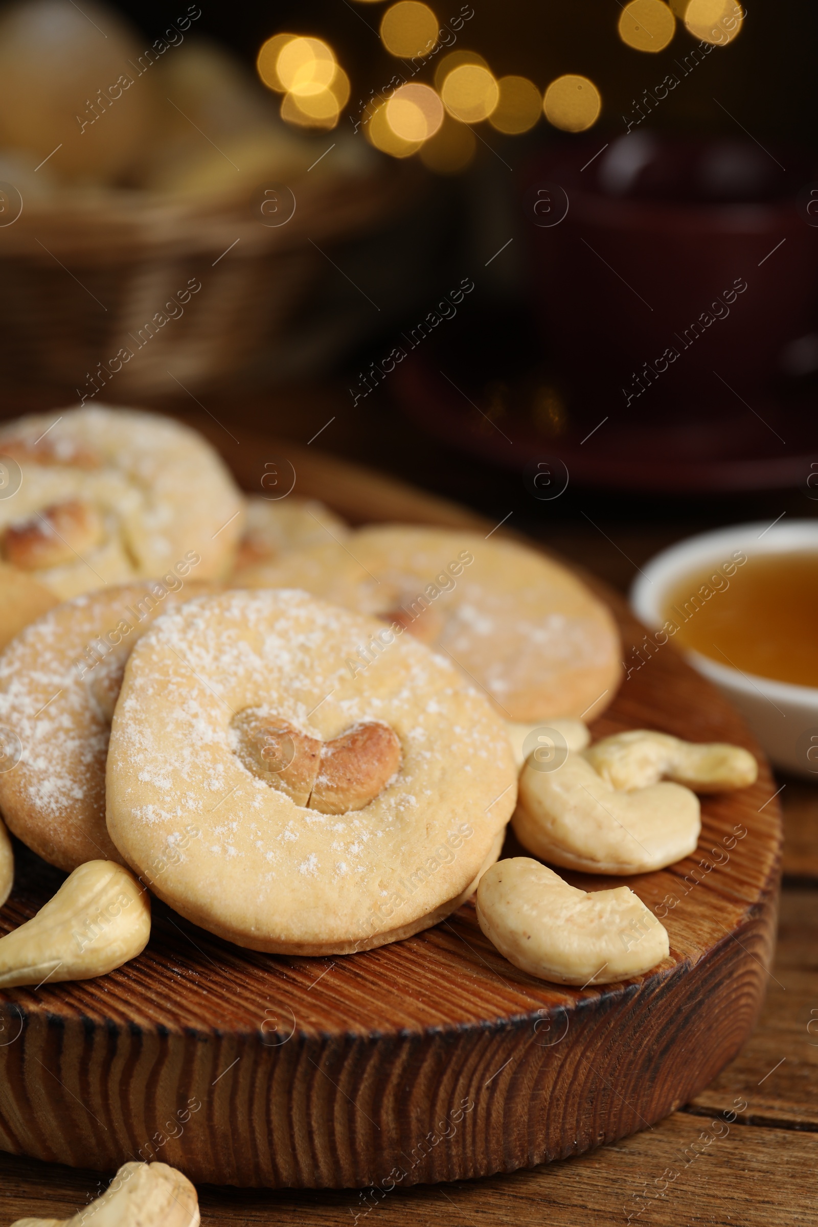 Photo of Tasty cashew cookies with powdered sugar on wooden table, closeup