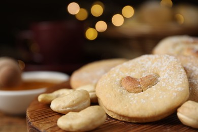 Photo of Tasty cashew cookies with powdered sugar on table, closeup. Space for text