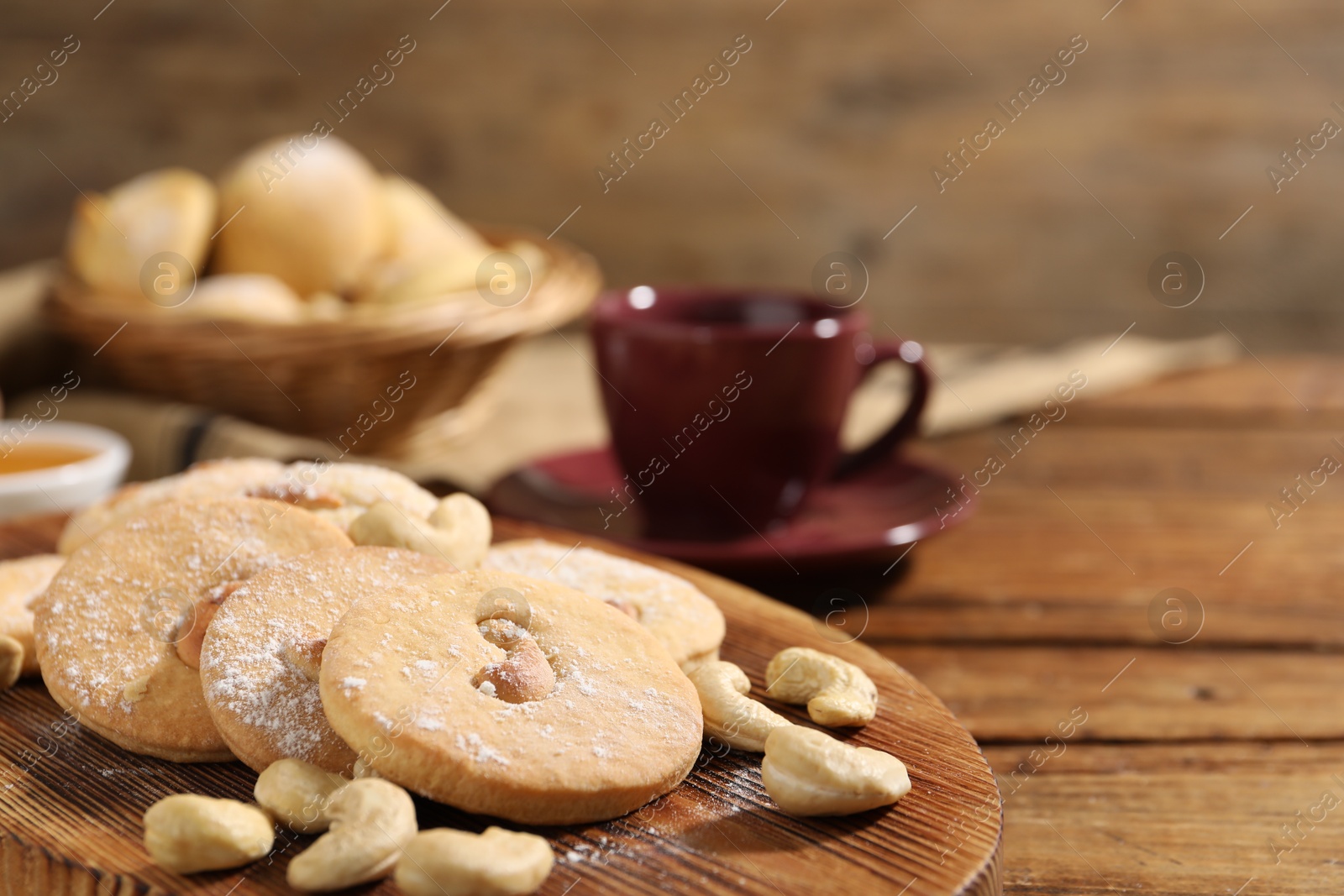 Photo of Tasty cashew cookies with powdered sugar on wooden table, closeup. Space for text