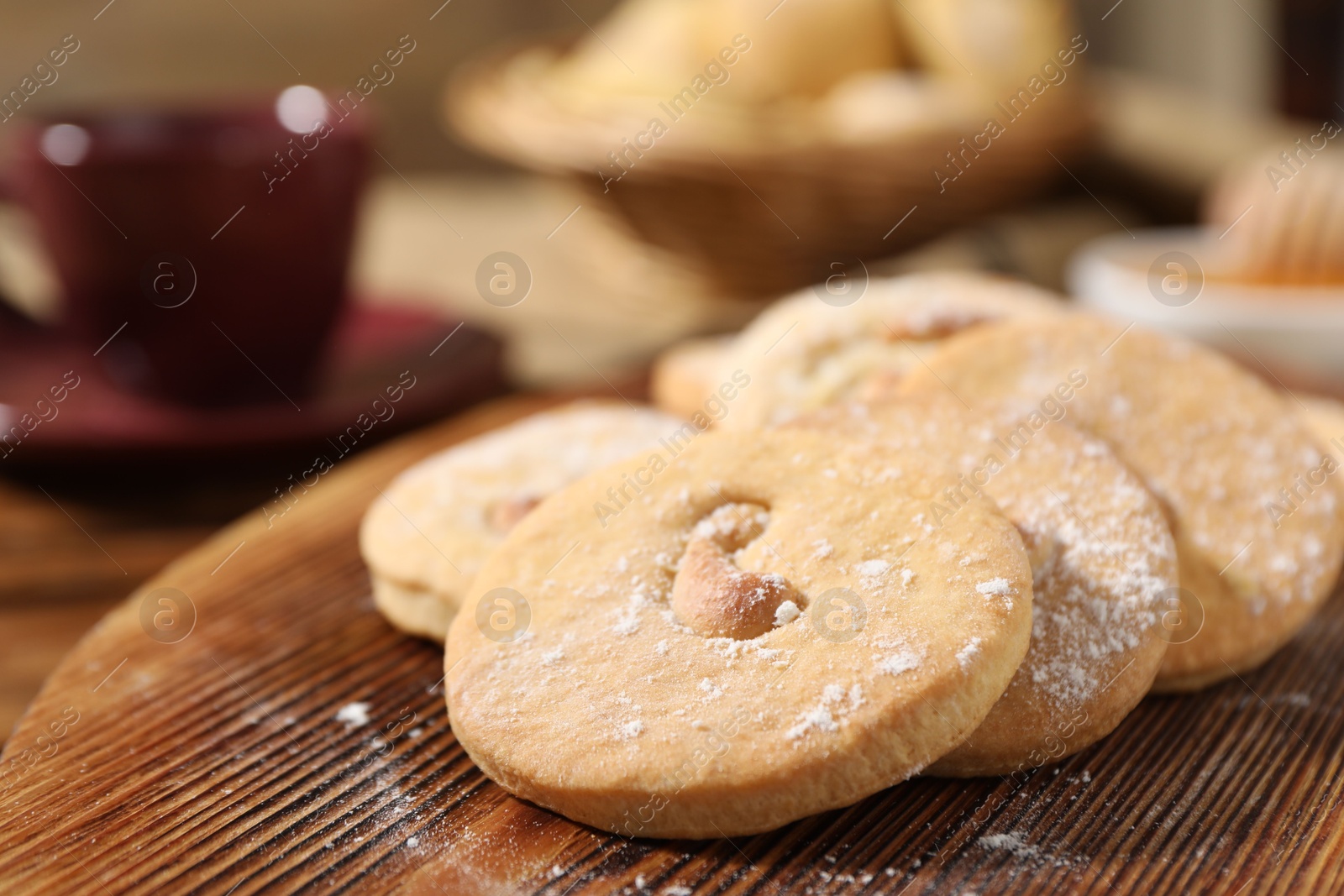 Photo of Tasty cashew cookies with powdered sugar on wooden board, closeup