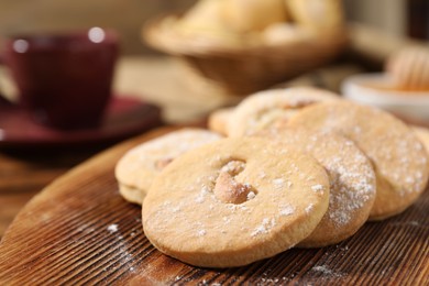 Photo of Tasty cashew cookies with powdered sugar on wooden board, closeup