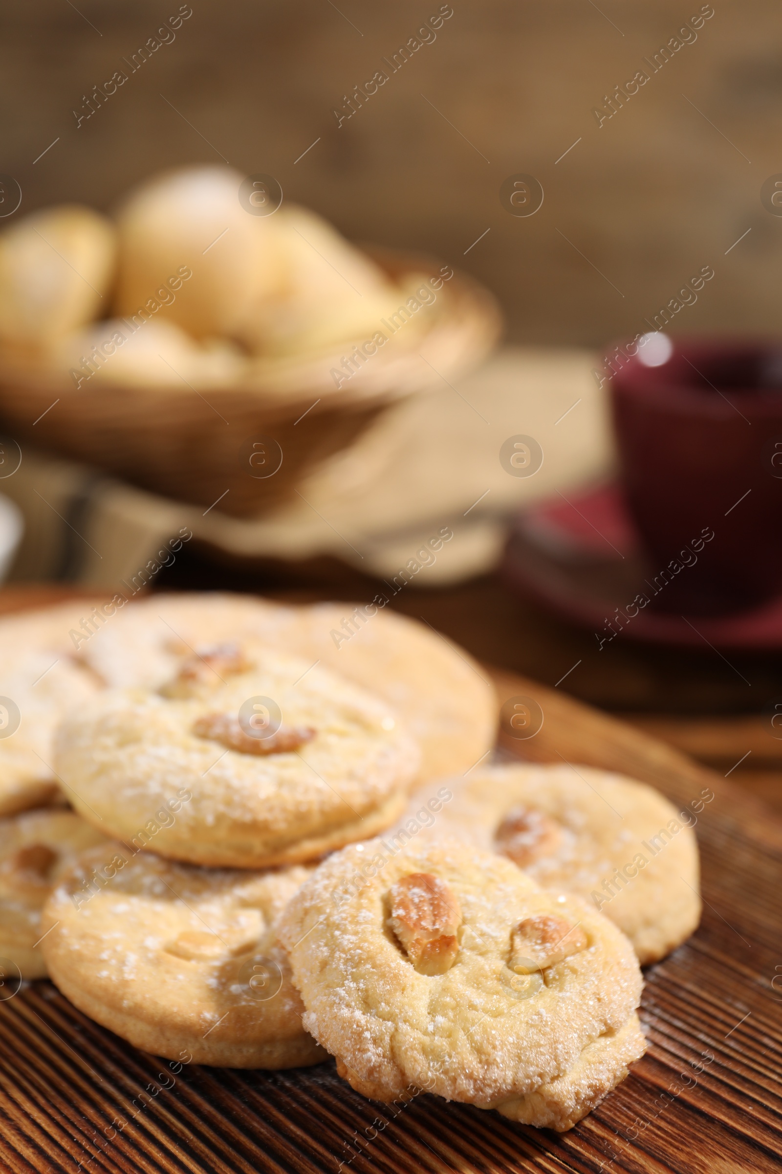 Photo of Tasty cashew cookies with powdered sugar on wooden board, closeup