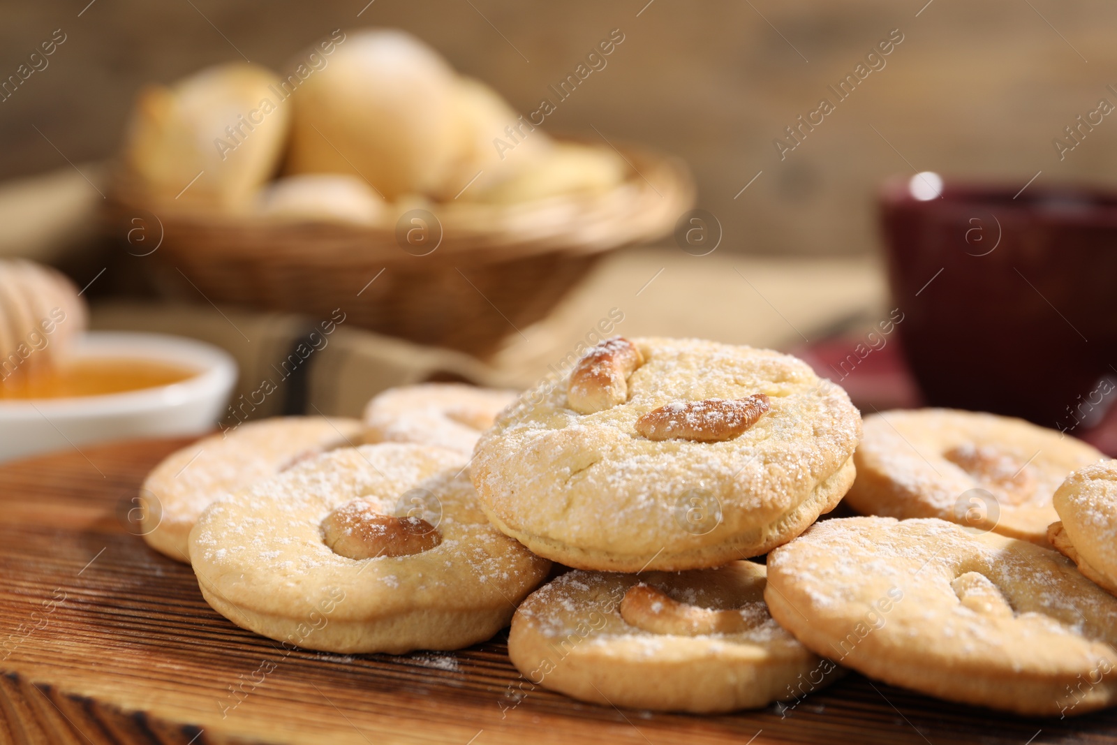 Photo of Tasty cashew cookies with powdered sugar on wooden board, closeup