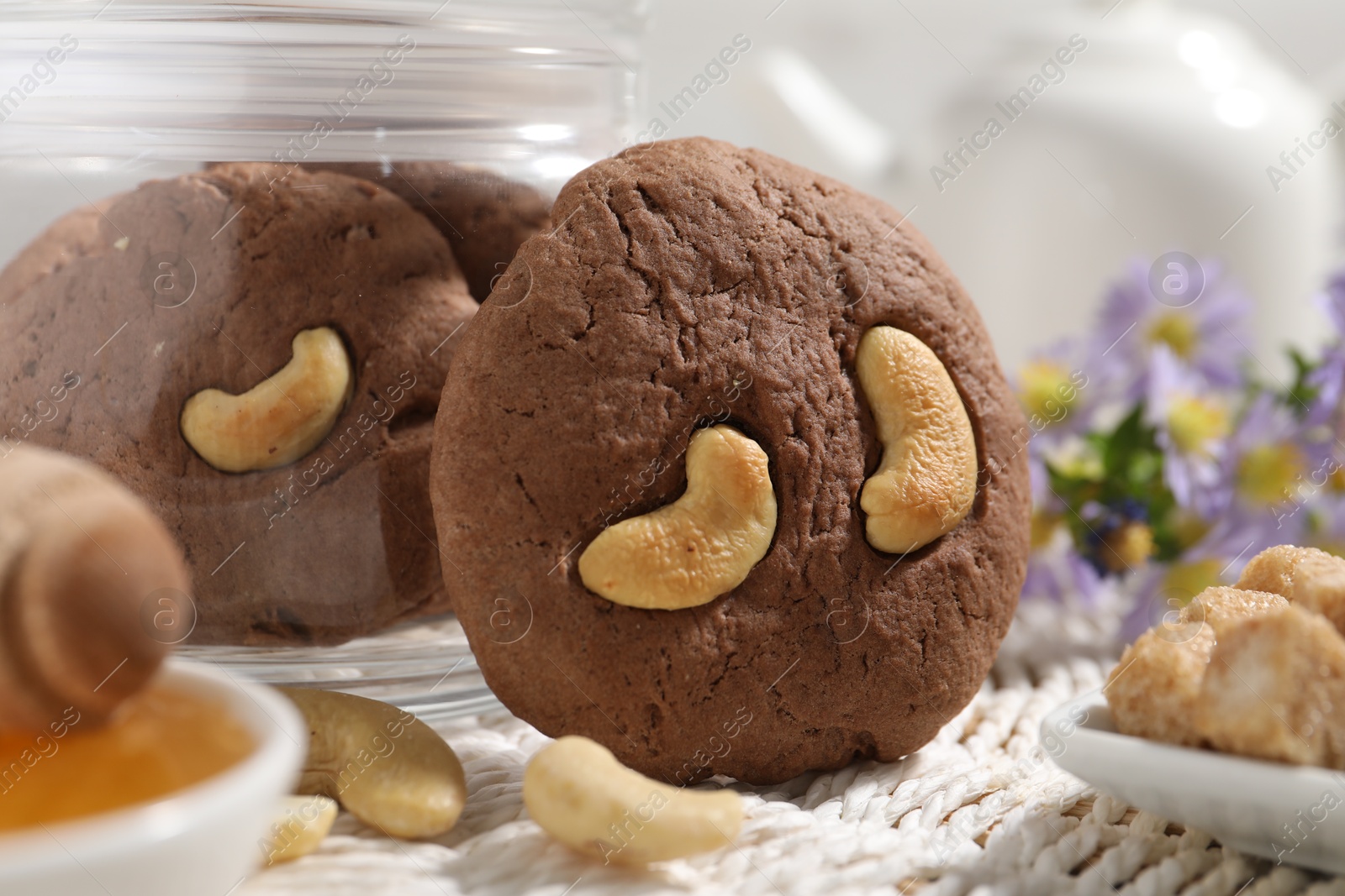 Photo of Tasty chocolate cookies with cashew on wicker mat, closeup