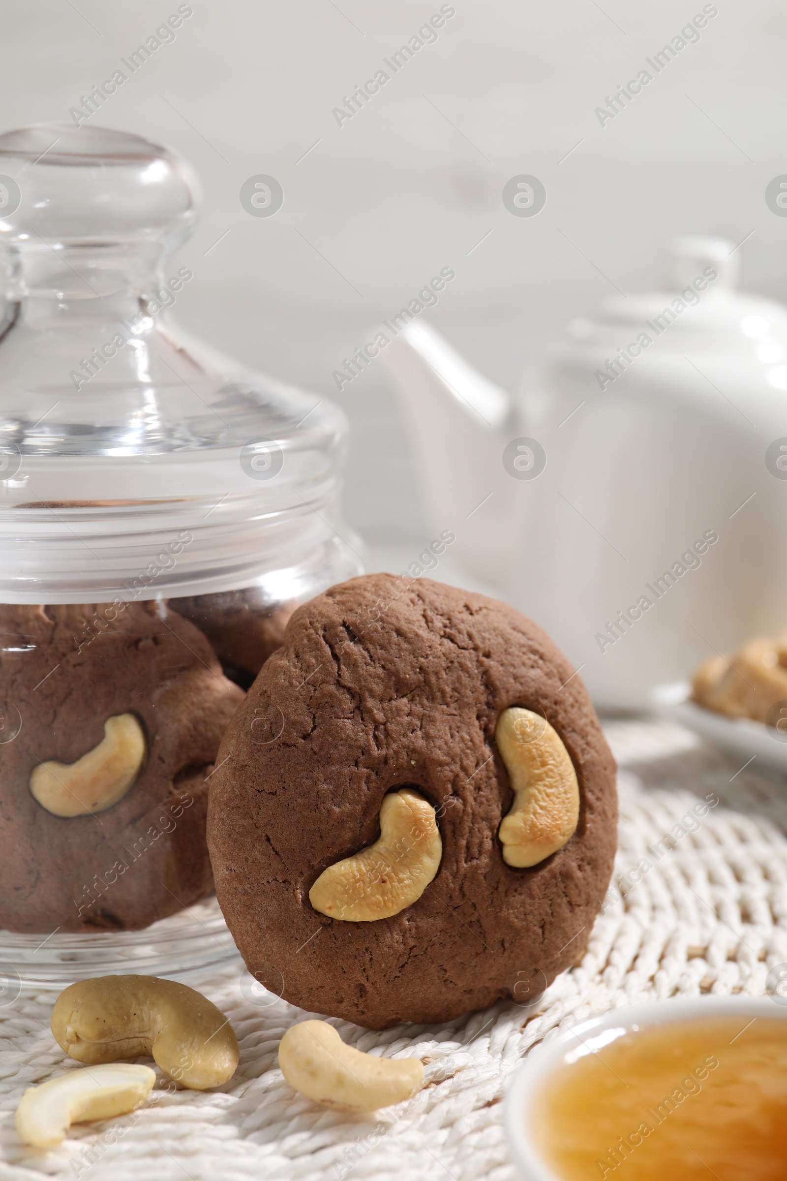 Photo of Tasty chocolate cookies with cashew on wicker mat, closeup