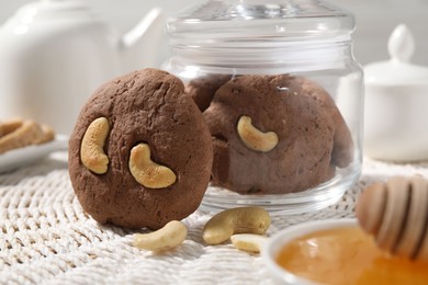 Photo of Tasty chocolate cookies with cashew and honey on wicker mat, closeup