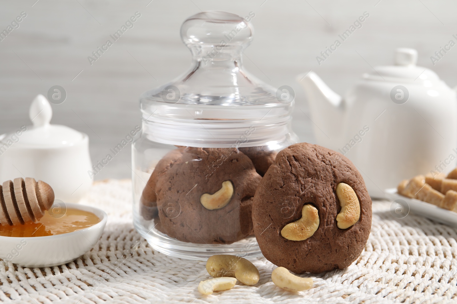 Photo of Tasty chocolate cookies with cashew and honey on wicker mat, closeup