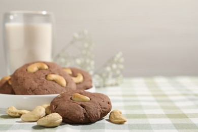 Photo of Tasty chocolate cookies with cashew on table, closeup. Space for text