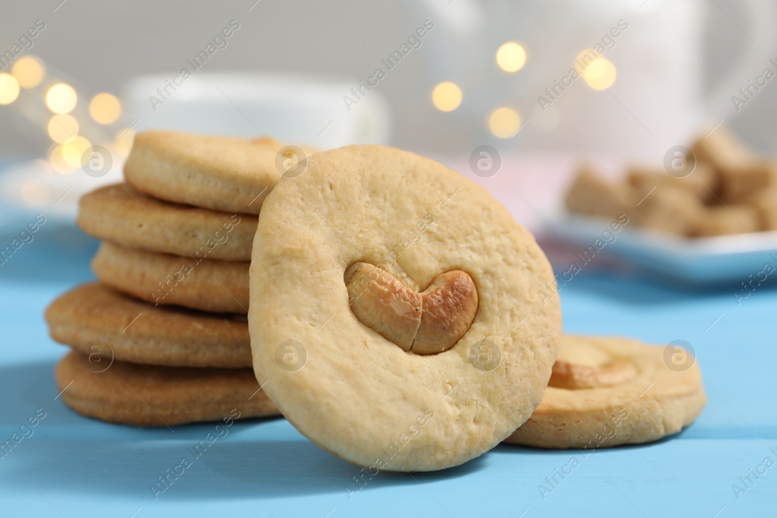 Photo of Tasty cashew cookies on light blue wooden table, closeup