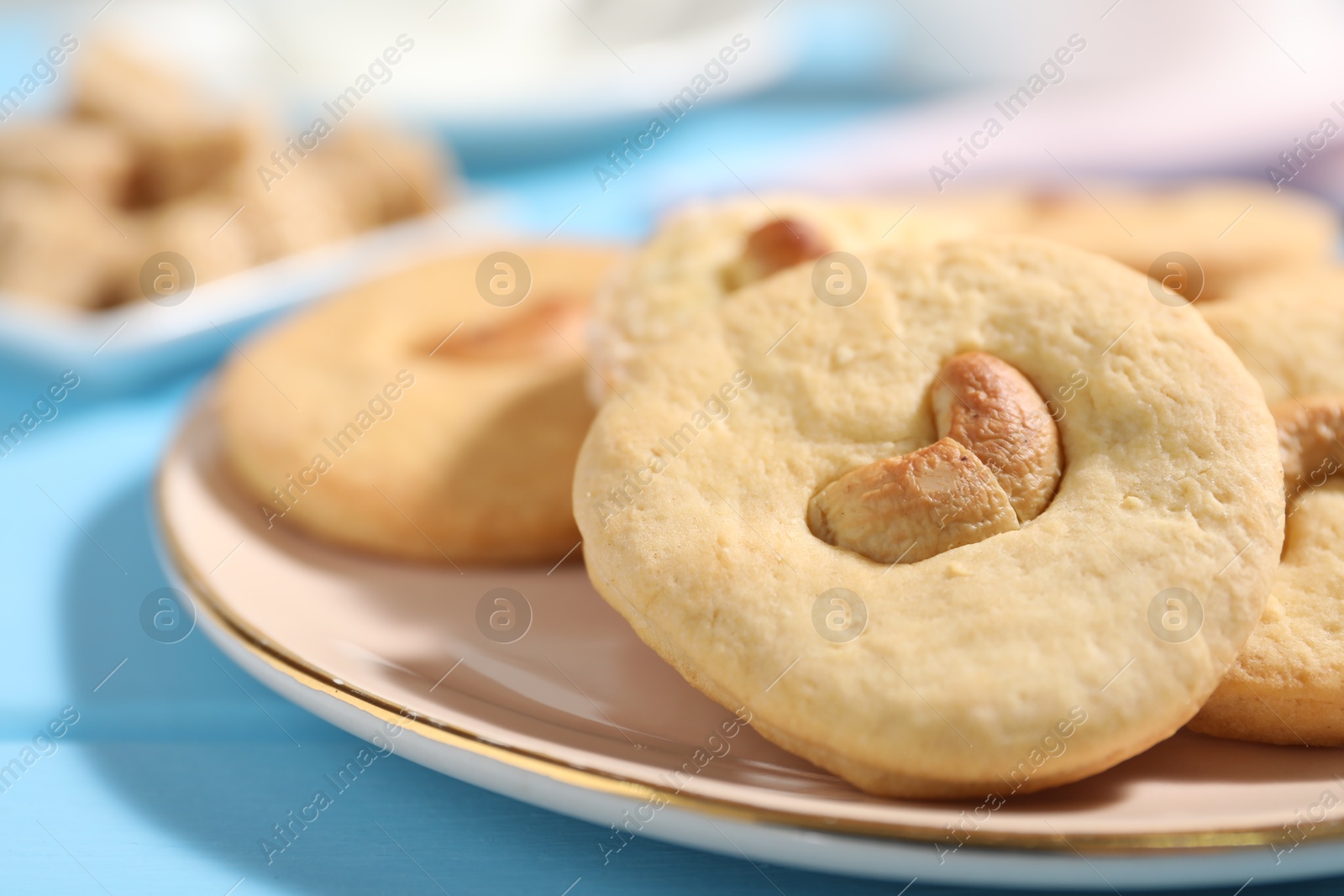 Photo of Plate with tasty cashew cookies on light blue wooden table, closeup