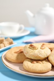 Photo of Plate with tasty cashew cookies on light blue wooden table, closeup