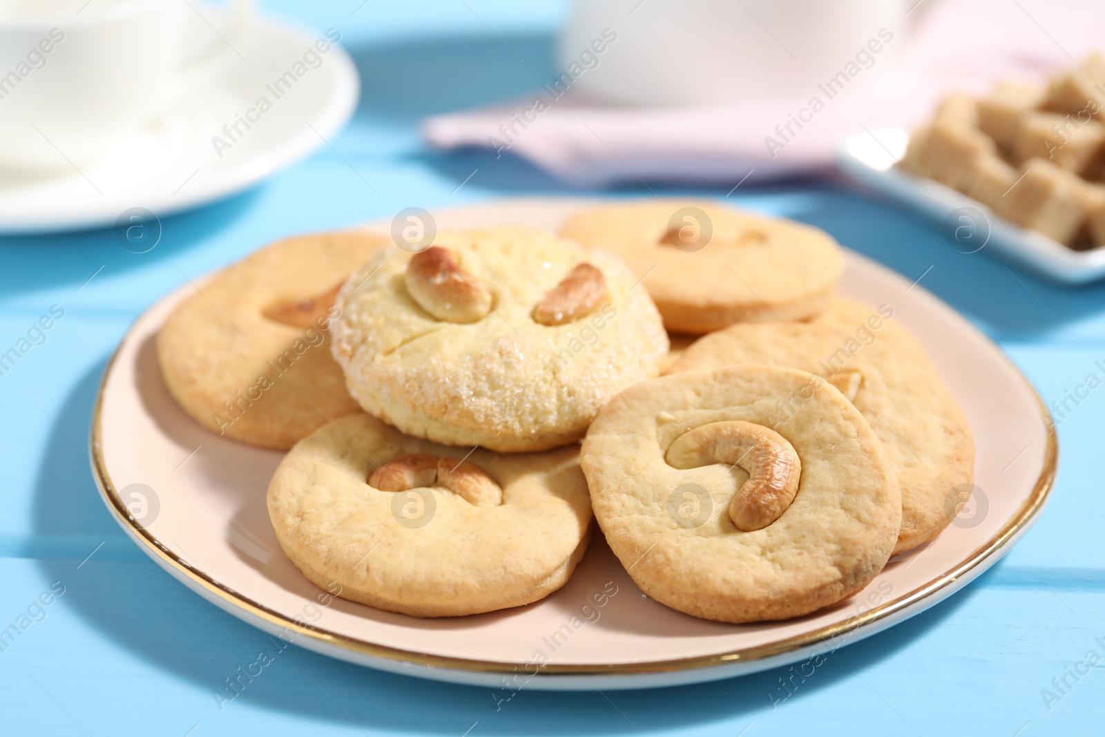 Photo of Plate with tasty cashew cookies on light blue wooden table, closeup