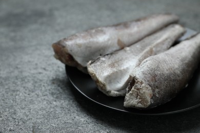 Photo of Frozen hake fishes on grey table, closeup