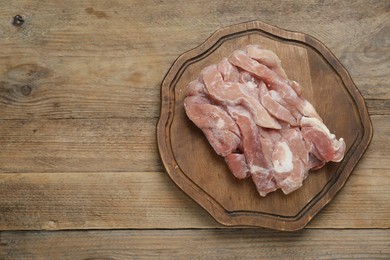 Photo of Frozen pieces of chicken fillet on wooden table, top view. Space for text