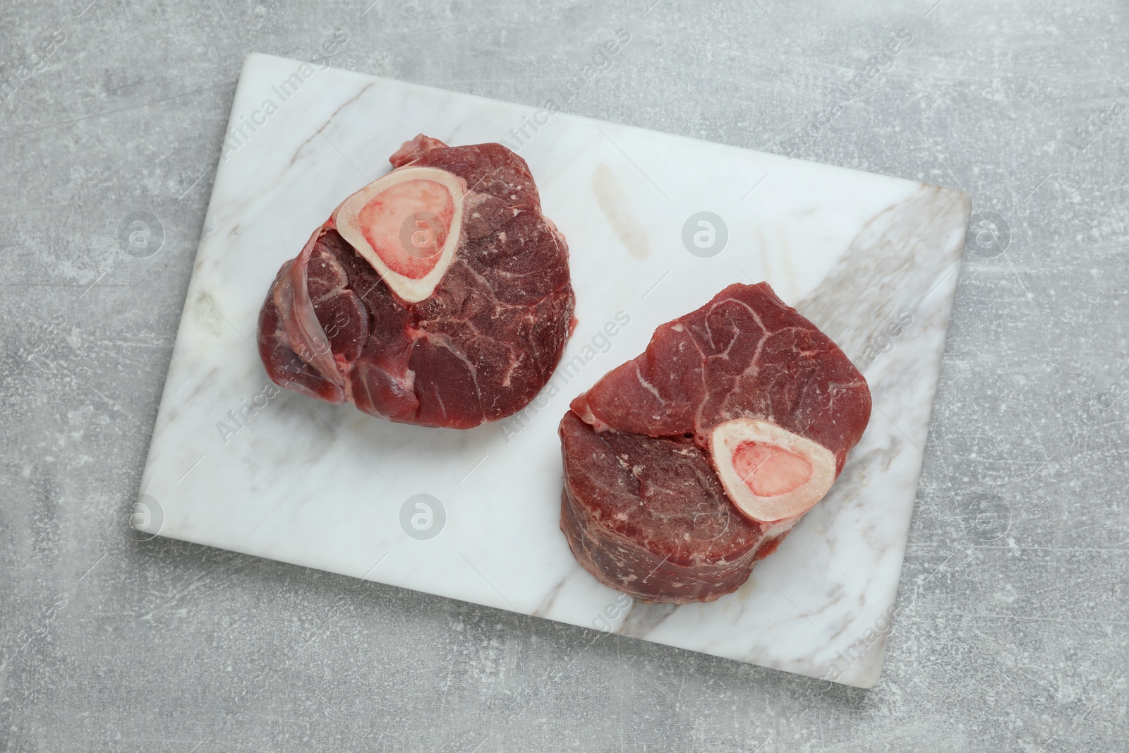 Photo of Frozen beef steaks on grey table, top view