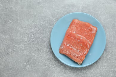 Photo of Frozen piece of salmon on grey table, top view. Space for text