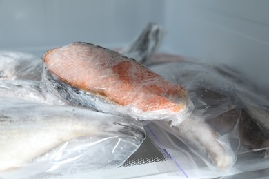 Photo of Different frozen fishes in plastic bags on refrigerator shelf, closeup