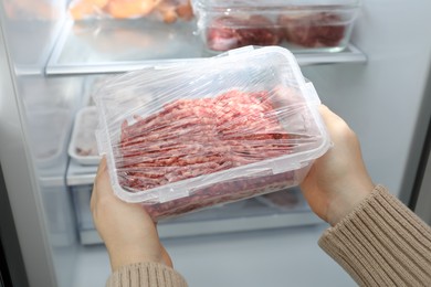 Photo of Woman taking frozen minced meat out of fridge, closeup